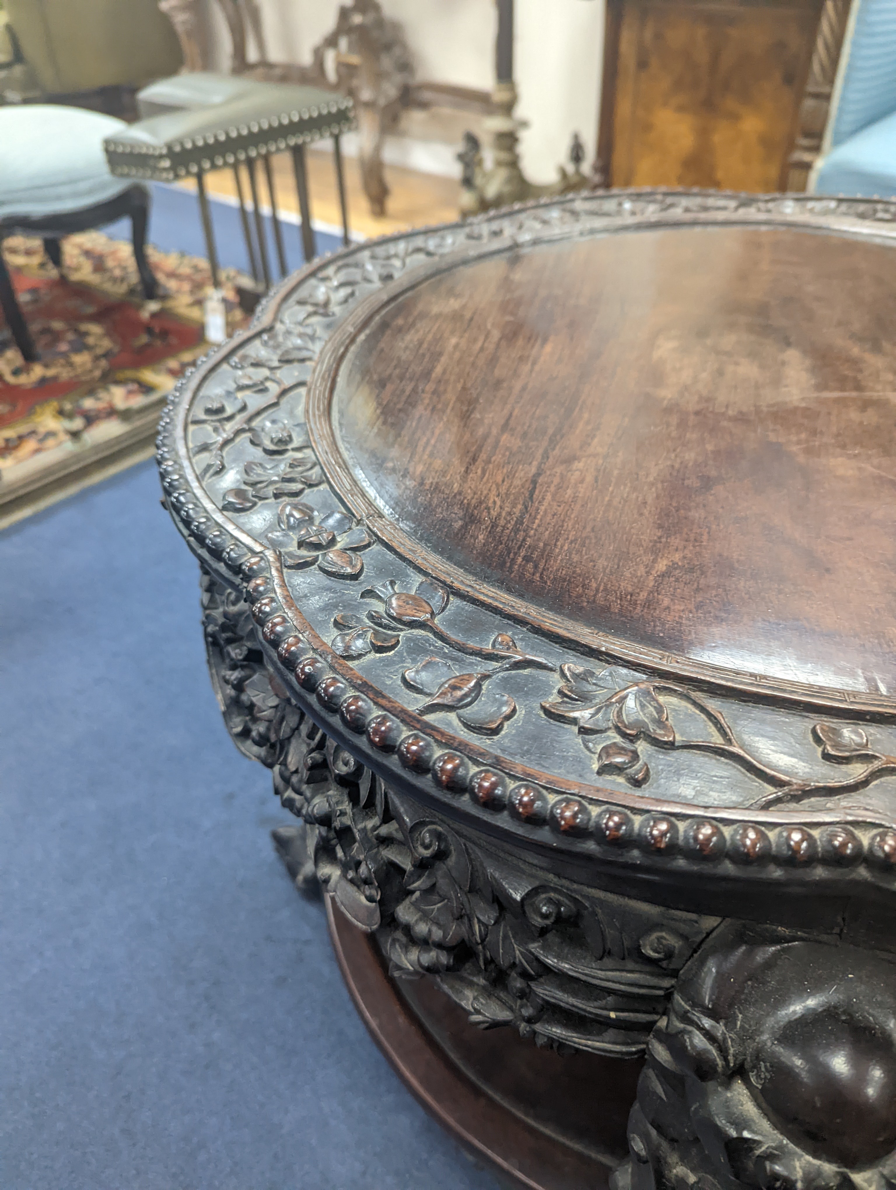 An early 20th century Chinese carved hardwood two tier table, diameter 64cm, height 56cm